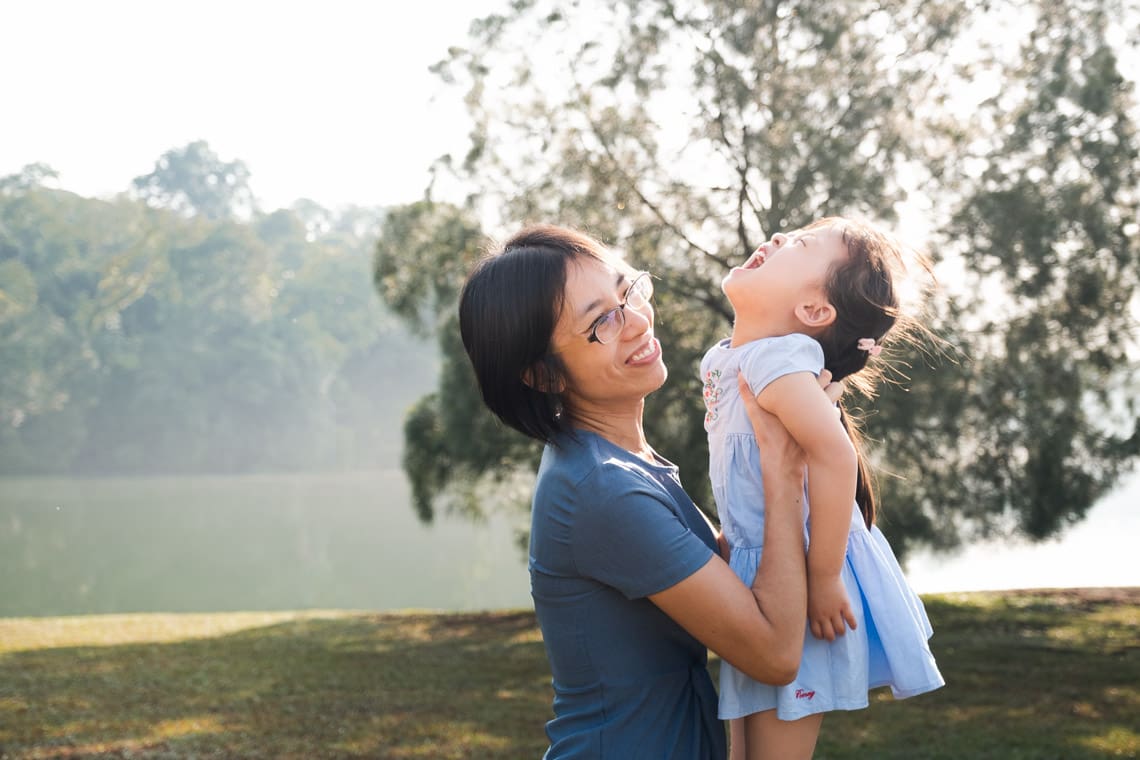 Mom holding his toddler daughter next to a beautiful reservoir