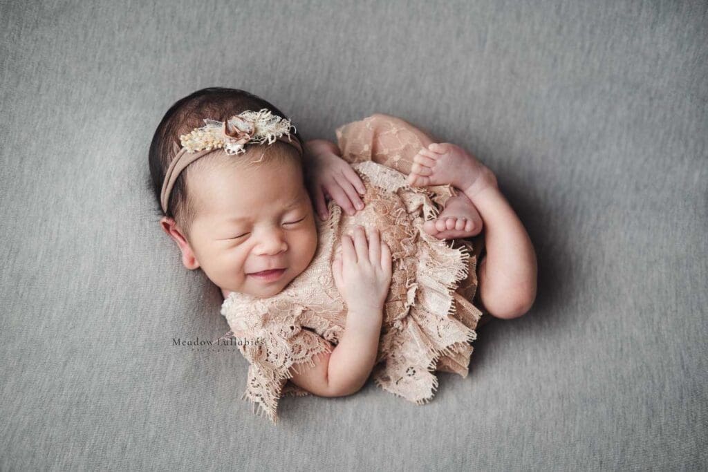 Newborn Photography Singapore Newborn girl posing and smiling on grey background
