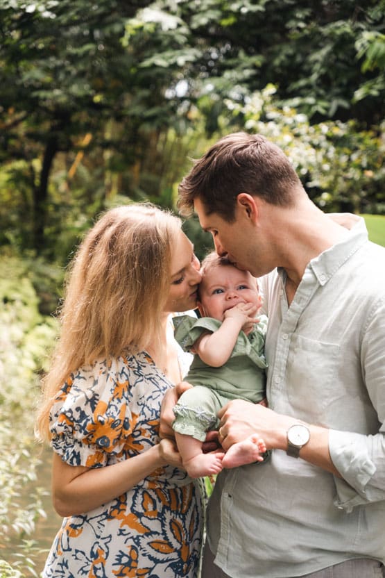 Lifestyle family photography Parents kissing baby in outdoor photoshoot