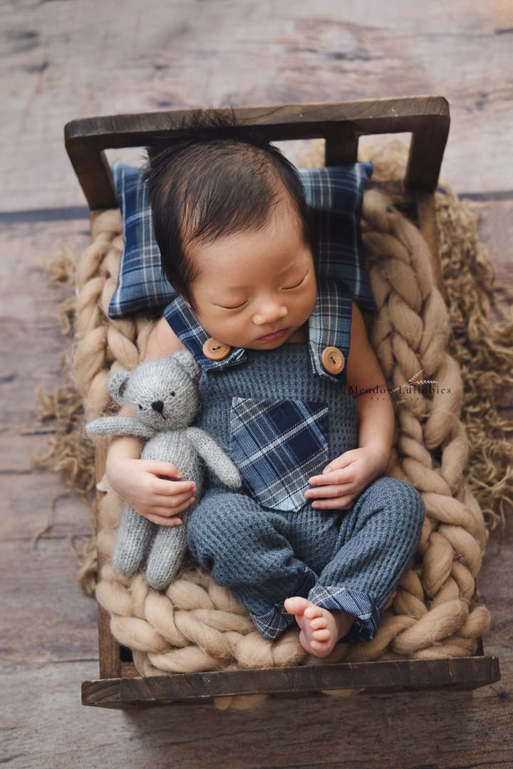 Newborn photography a baby sleeping in bed clutching teddy bear