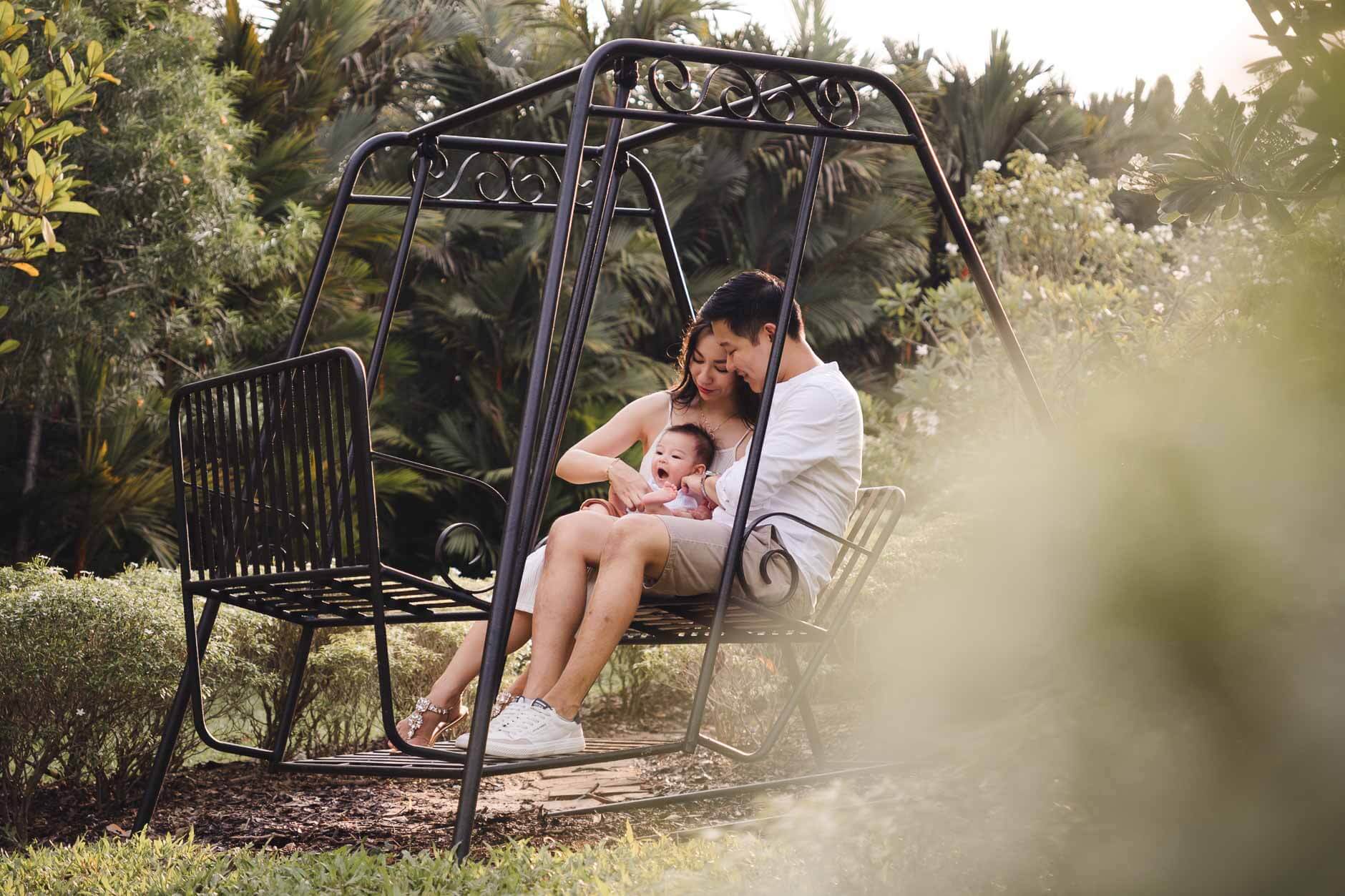 Parents sitting on swing with their 1 year old baby