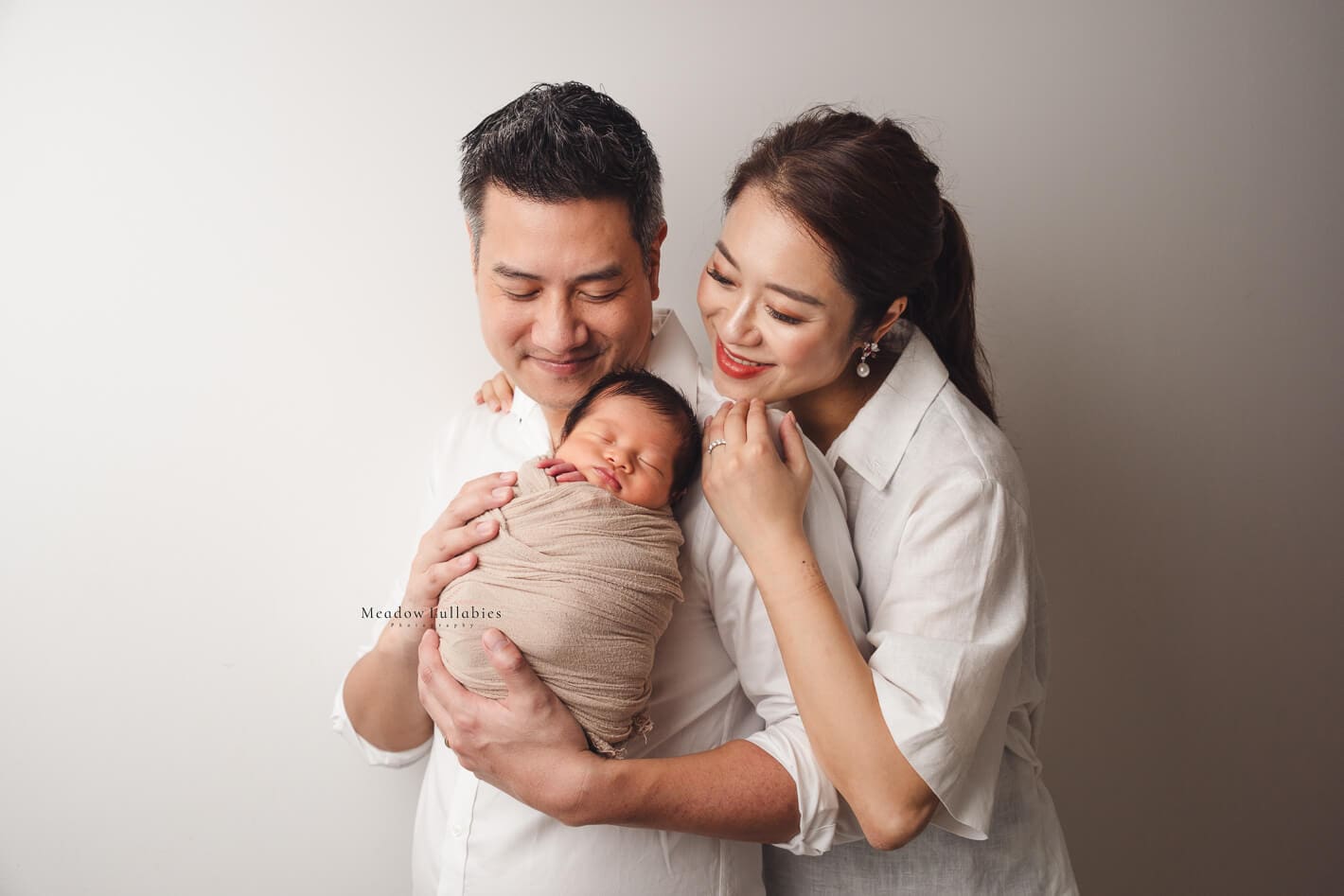 Newborn photoshoot parents happily smiling at their newborn baby