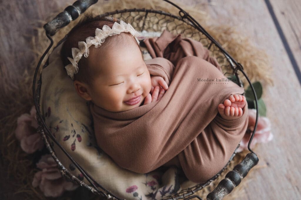 Newborn Photography Singapore Newborn baby in peeky toes wrap smiling in steel crate prop